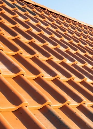 Overlapping rows of yellow ceramic roofing tiles covering residential building roof.